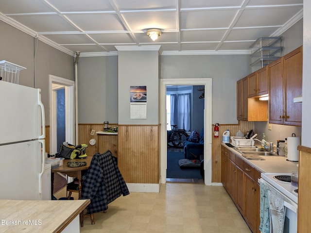 kitchen featuring white appliances, wainscoting, brown cabinets, light floors, and a sink