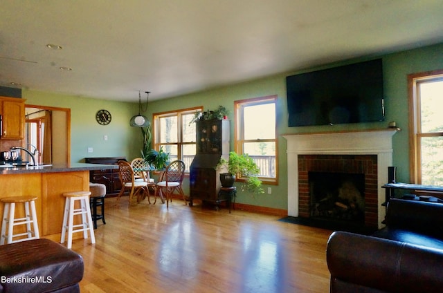 living room with light hardwood / wood-style flooring and a brick fireplace