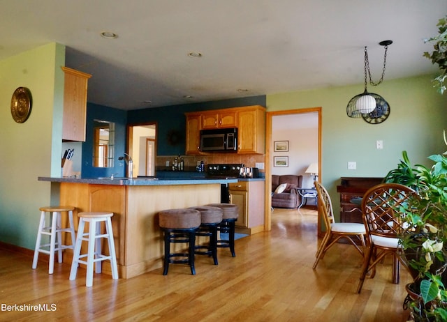 kitchen featuring a kitchen bar, kitchen peninsula, sink, and light hardwood / wood-style floors