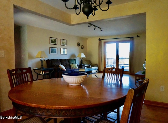 dining area featuring hardwood / wood-style floors, rail lighting, and an inviting chandelier