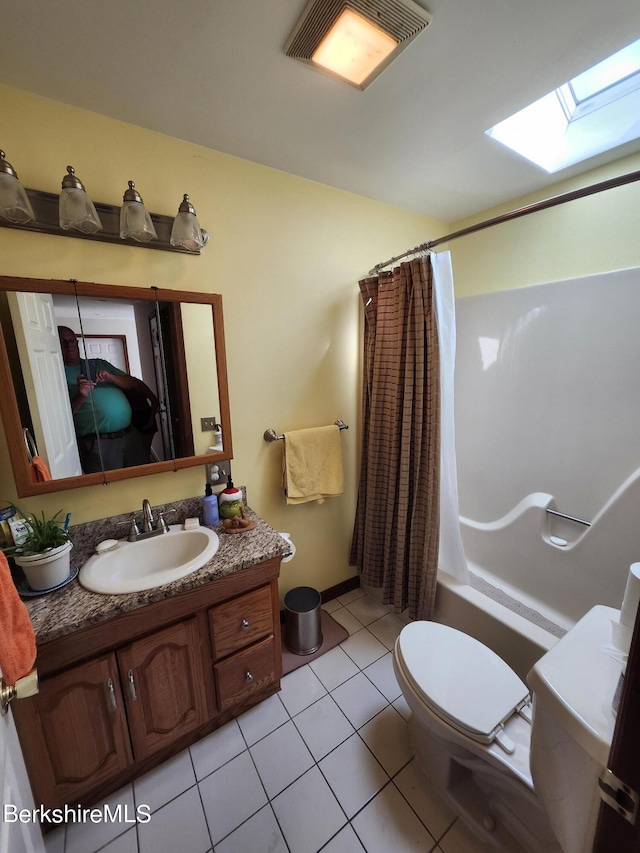 full bathroom with a skylight, vanity, shower / tub combo, toilet, and tile patterned floors