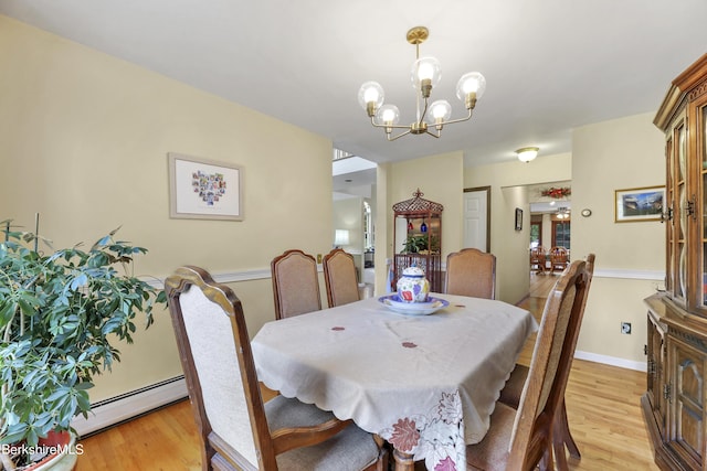 dining area with light hardwood / wood-style flooring, a chandelier, and baseboard heating