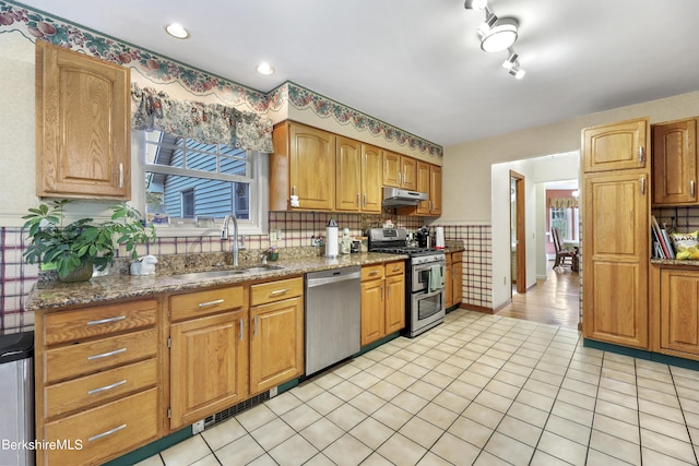 kitchen with sink, appliances with stainless steel finishes, dark stone countertops, tasteful backsplash, and light tile patterned flooring