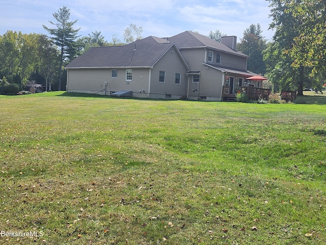 back of property featuring a wooden deck and a lawn