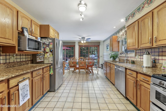 kitchen with light tile patterned flooring, sink, decorative backsplash, stainless steel appliances, and light stone countertops