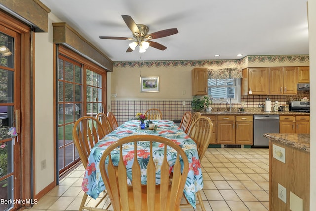 tiled dining space featuring ceiling fan, sink, and a healthy amount of sunlight