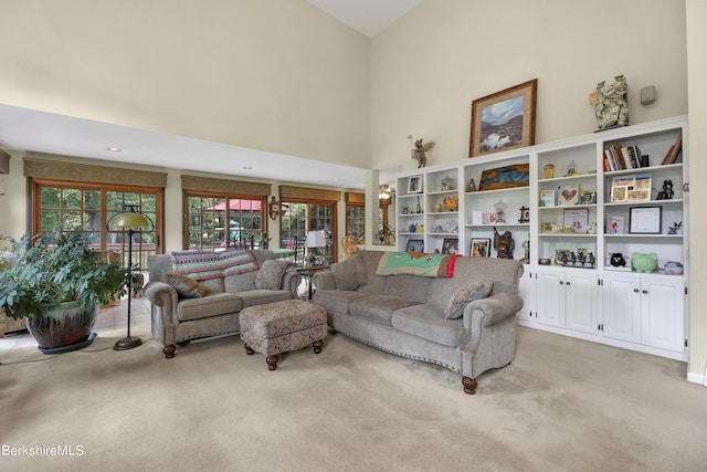 living room featuring a healthy amount of sunlight, light colored carpet, and a high ceiling