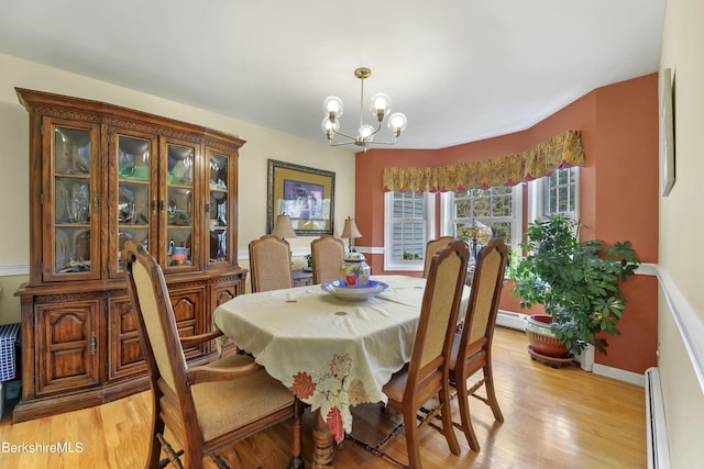 dining space with light wood-type flooring, a baseboard radiator, and an inviting chandelier