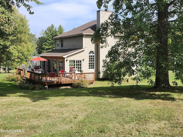 rear view of property featuring a wooden deck and a lawn