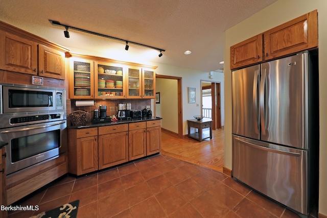 55 Mallard Dr, Becket, MA 01223 - kitchen featuring stainless steel appliances, brown cabinets, dark countertops, tasteful backsplash, and a textured ceiling