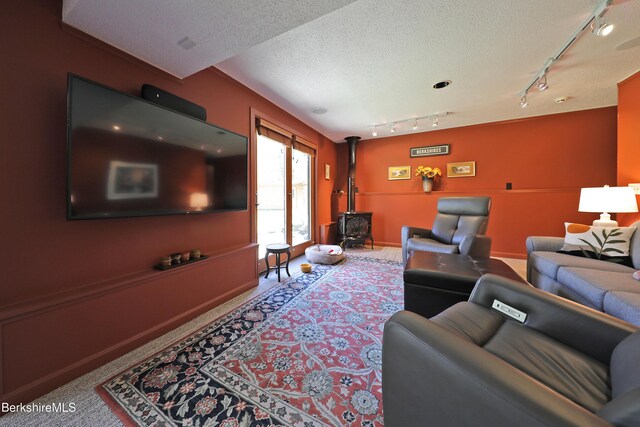55 Mallard Dr, Becket, MA 01223 - carpeted living room with a wood stove, rail lighting, and a textured ceiling