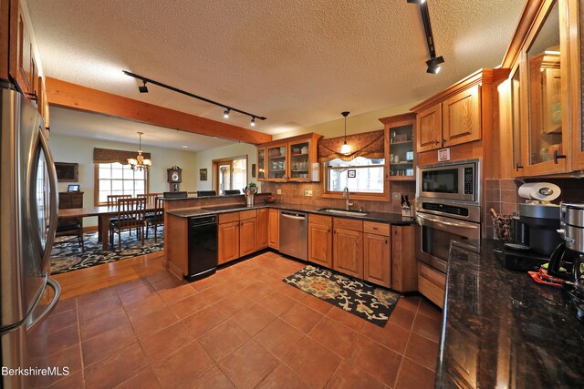 55 Mallard Dr, Becket, MA 01223 - kitchen featuring stainless steel appliances, track lighting, brown cabinets, a peninsula, and a chandelier