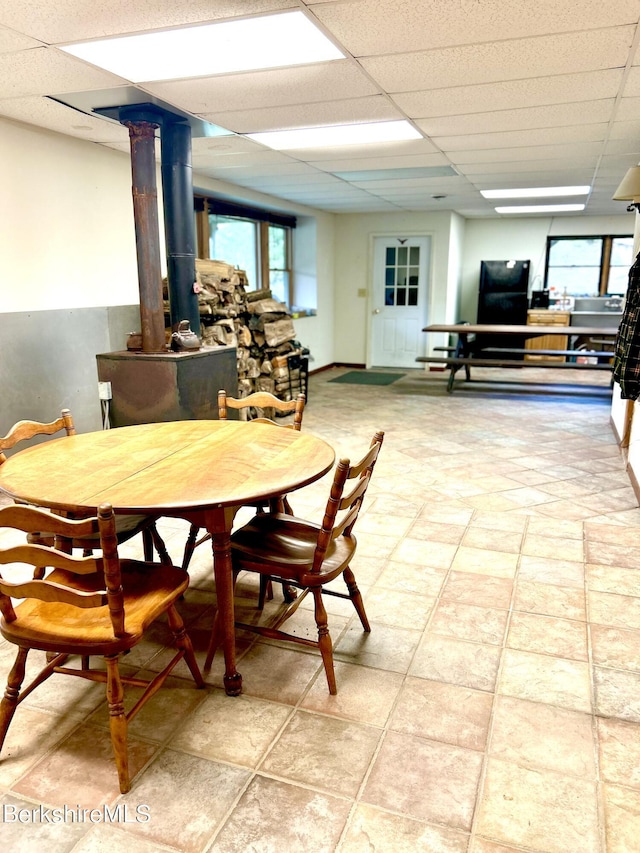 dining room with a wood stove and a drop ceiling