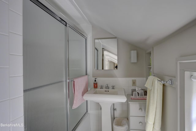 bathroom with a shower with door, tile walls, and sink