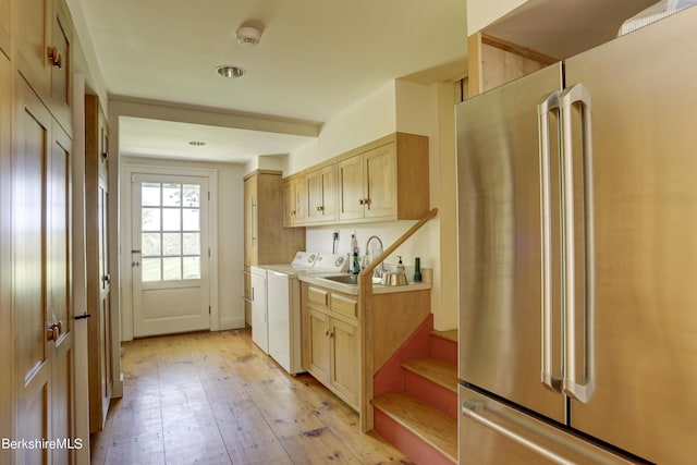 kitchen with light brown cabinetry, high end fridge, washer and clothes dryer, sink, and light hardwood / wood-style floors