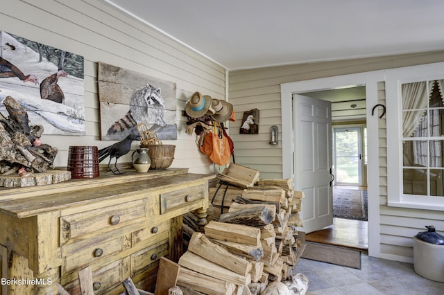 mudroom featuring light tile patterned floors, vaulted ceiling, and wood walls