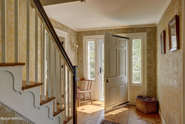 entrance foyer with crown molding and light hardwood / wood-style floors