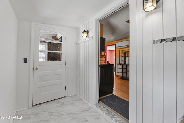 doorway to outside with an AC wall unit and marble finish floor