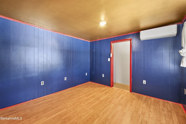 spare room featuring wood finished floors and a wall mounted air conditioner