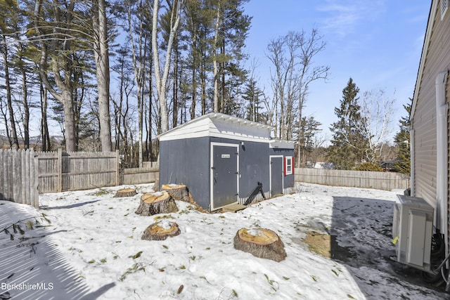 yard covered in snow with a shed, a fenced backyard, and an outbuilding