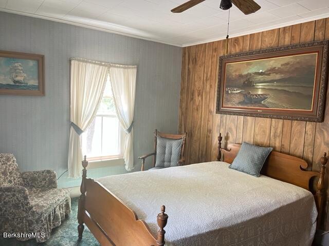 bedroom with ceiling fan and wooden walls