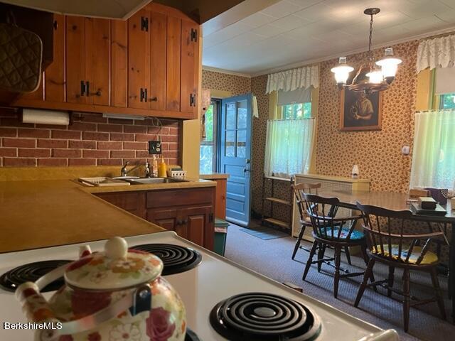 kitchen featuring pendant lighting, white stove, a notable chandelier, and sink