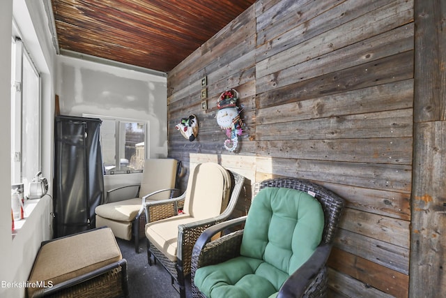 sitting room featuring wood ceiling, wooden walls, and plenty of natural light