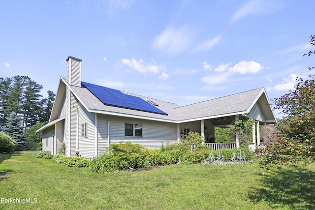 83 Hancock Rd, Pittsfield, MA 01201 - view of home's exterior with a porch, a lawn, roof mounted solar panels, a chimney, and a shingled roof