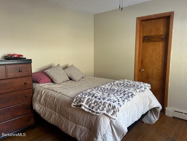 bedroom with dark hardwood / wood-style flooring and baseboard heating