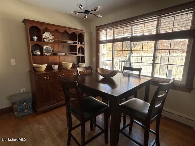 dining area with a baseboard radiator, dark hardwood / wood-style floors, and an inviting chandelier