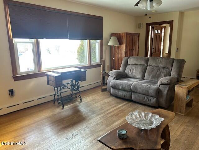 living room featuring a baseboard radiator, ceiling fan, and light hardwood / wood-style flooring