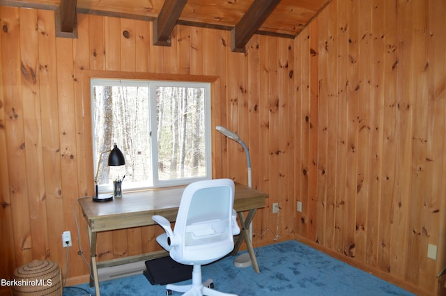 carpeted home office featuring wooden walls and beamed ceiling