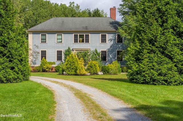 view of front of home with driveway, a front lawn, and a chimney