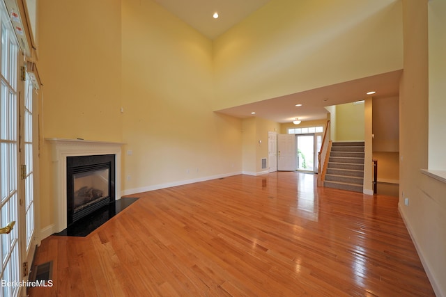 33 Alpine Trl, Pittsfield, MA 01201 - unfurnished living room with a fireplace with flush hearth, light wood-style floors, stairs, baseboards, and a high ceiling