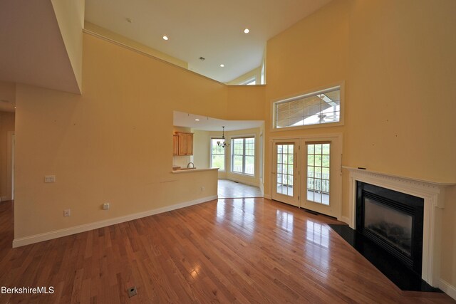 33 Alpine Trl, Pittsfield, MA 01201 - unfurnished living room with a fireplace with flush hearth, wood finished floors, a towering ceiling, baseboards, and recessed lighting