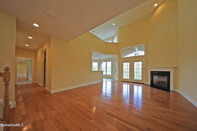 33 Alpine Trl, Pittsfield, MA 01201 - unfurnished living room with light wood finished floors, a fireplace with flush hearth, recessed lighting, baseboards, and a high ceiling