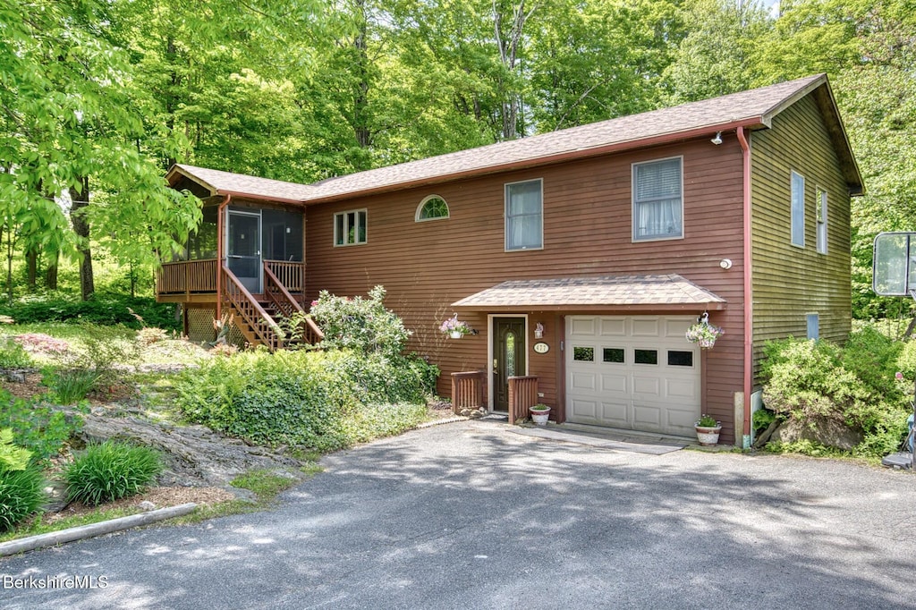 477 Greylock St, Lee, MA 01238 - rustic home featuring an attached garage, a sunroom, asphalt driveway, stairs, and a shingled roof