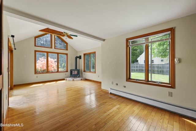 unfurnished living room with a wood stove, a baseboard radiator, ceiling fan, light wood-style flooring, and baseboards