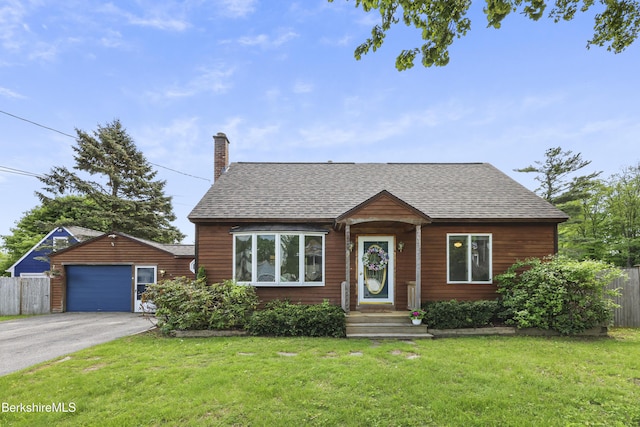 view of front facade featuring a shingled roof, driveway, a chimney, and a detached garage