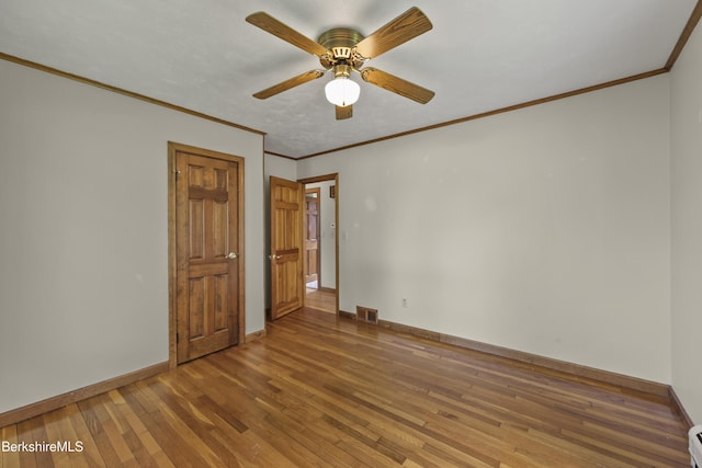 empty room featuring hardwood / wood-style floors, baseboards, ceiling fan, crown molding, and baseboard heating