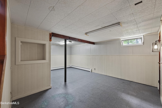 basement featuring tile patterned floors, wood walls, and wainscoting