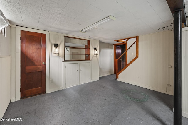 finished basement featuring tile patterned floors, stairway, and baseboards