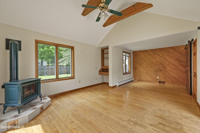 unfurnished living room with a baseboard heating unit, a wood stove, light wood-style flooring, wood walls, and high vaulted ceiling
