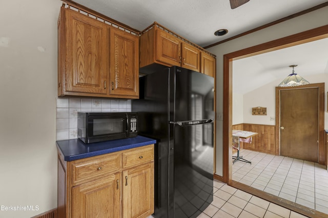 kitchen featuring black appliances, dark countertops, brown cabinets, wainscoting, and wooden walls