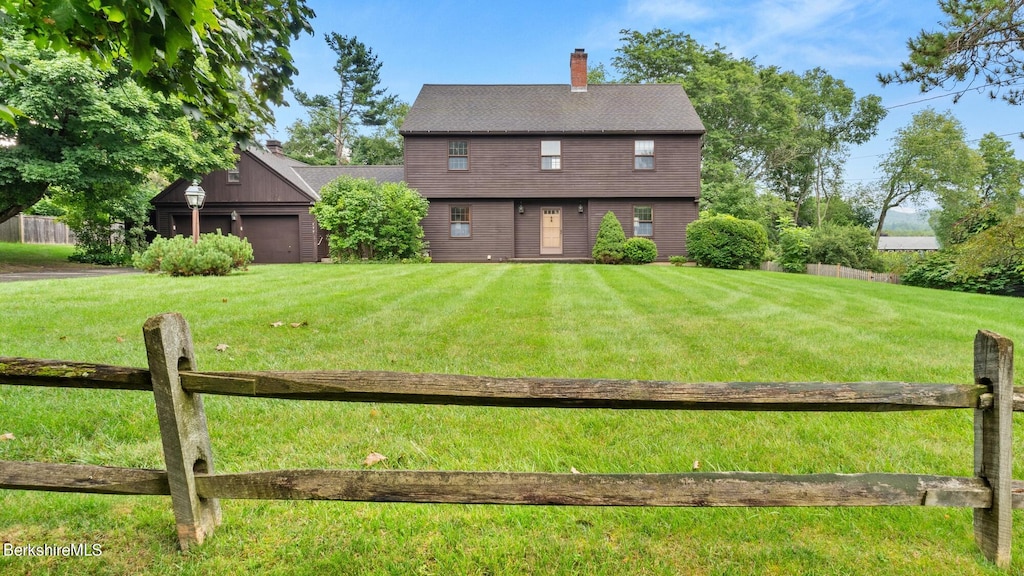 back of property with a yard, a garage, and an outdoor structure