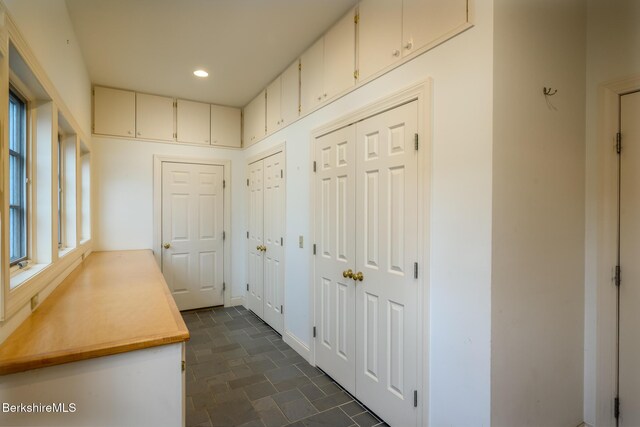 hall featuring recessed lighting, stone finish flooring, and baseboards