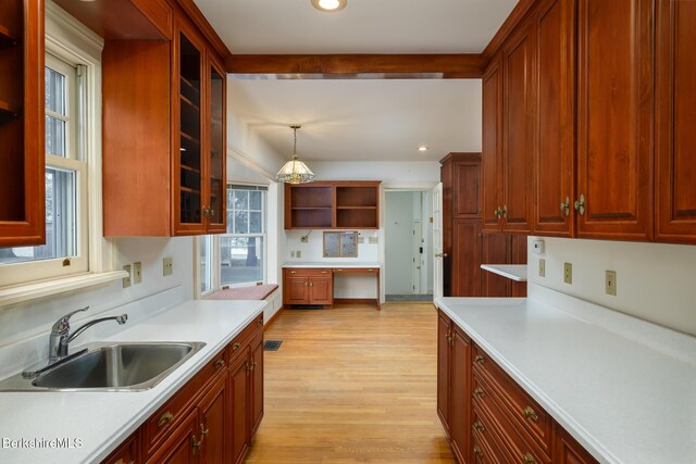 kitchen featuring a sink, glass insert cabinets, light wood-type flooring, light countertops, and open shelves