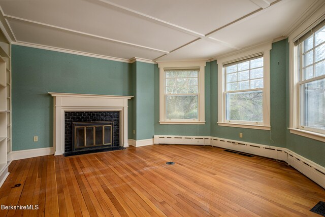 unfurnished living room with crown molding, a fireplace with flush hearth, a healthy amount of sunlight, and wood-type flooring