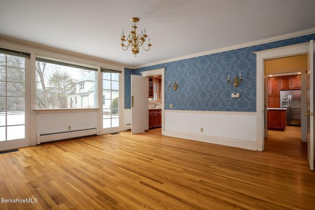 empty room with a wainscoted wall, light wood-style flooring, crown molding, wallpapered walls, and baseboard heating