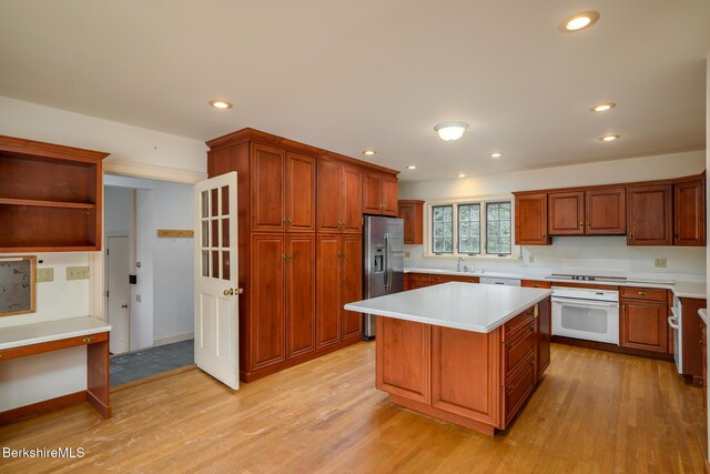 kitchen with white oven, light countertops, light wood-type flooring, and stainless steel fridge with ice dispenser